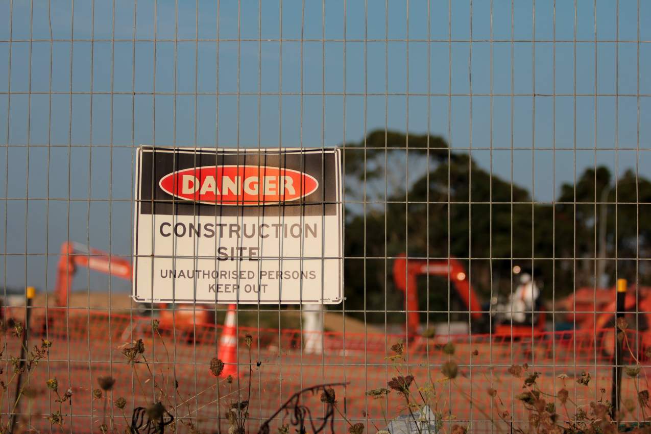 Wire fence around a construction site with a digger in the background