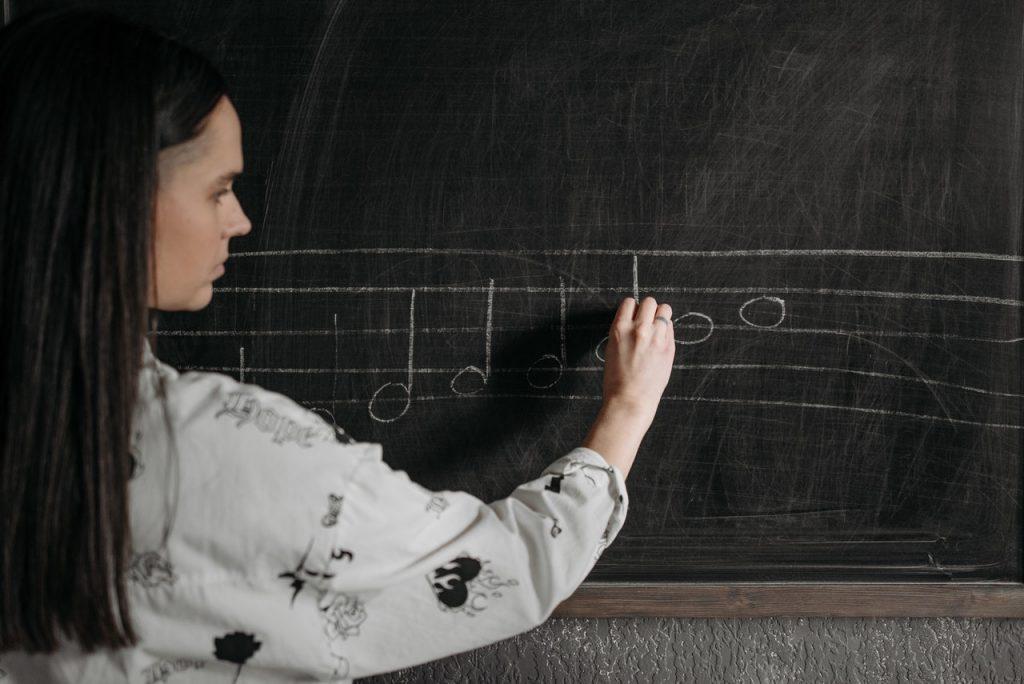 Music teacher writing notes on a blackboard