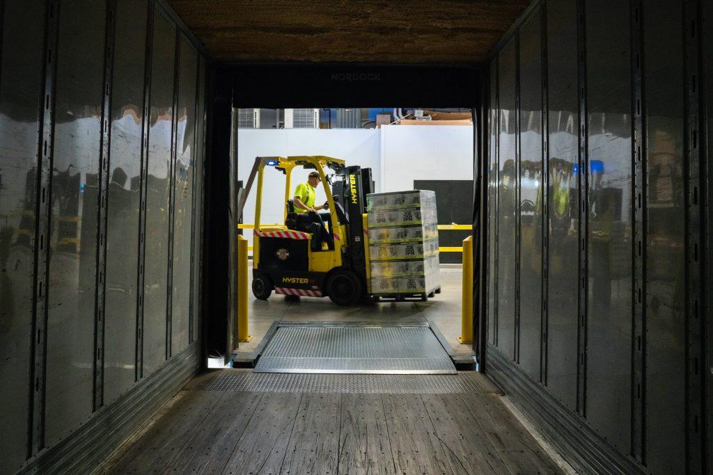 forklift truck carrying goods past a container