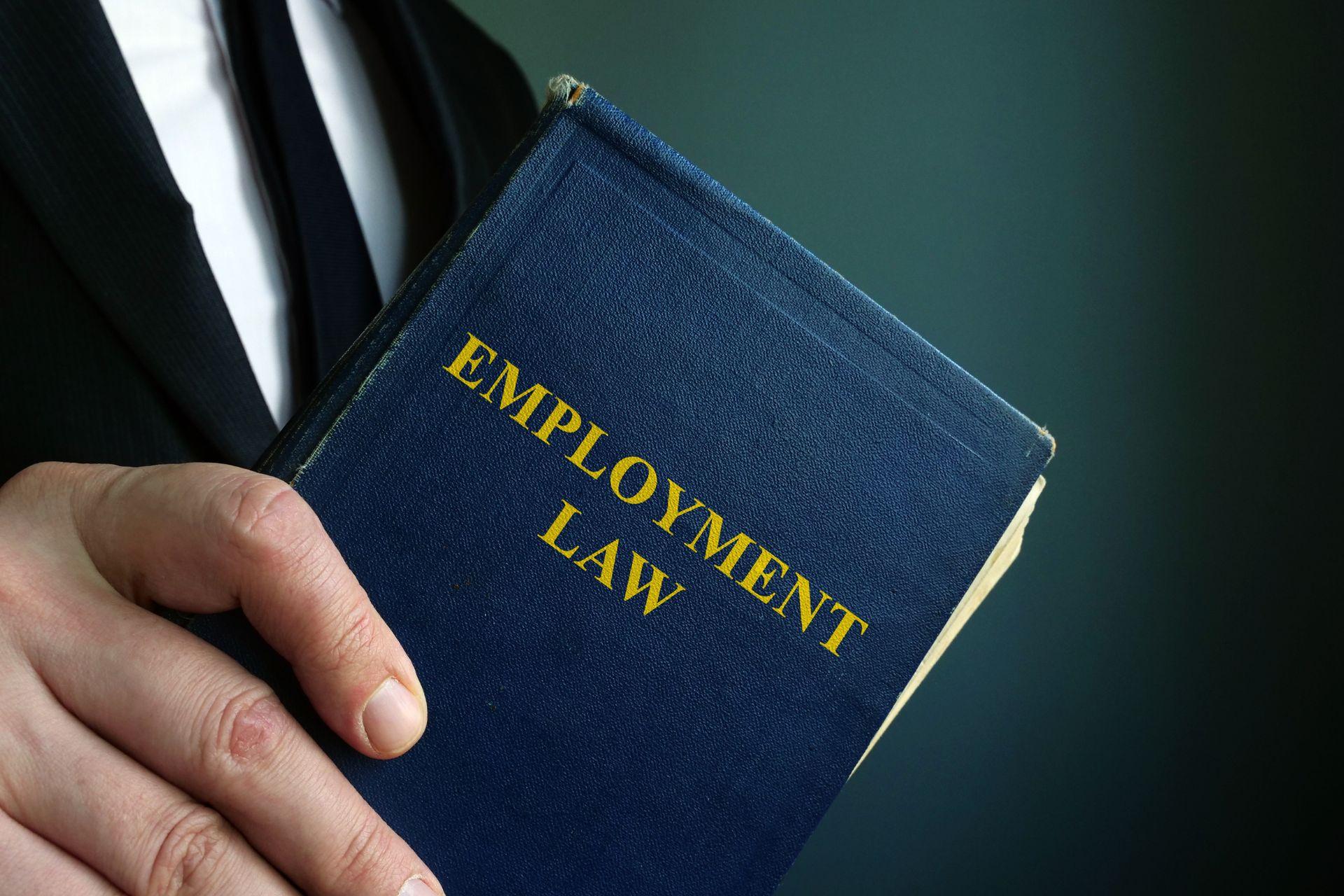 Man in a suit holding an employment law book