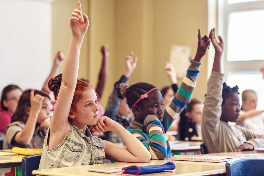 Children in a classroom with raised hands